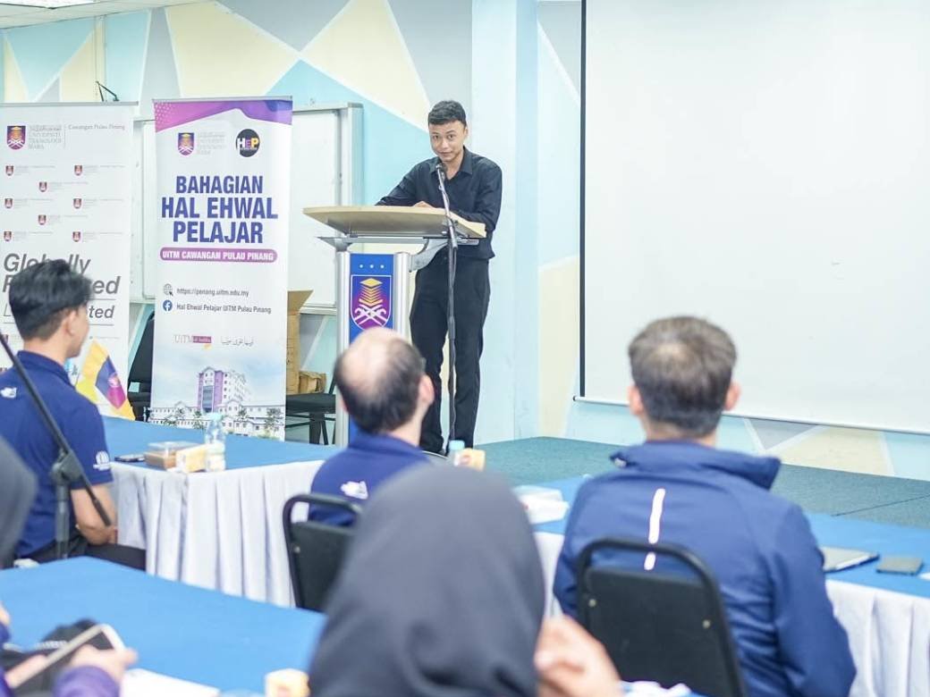 Carl presenting at a podium at HEP, UiTM Cawangan Pulau Pinang
